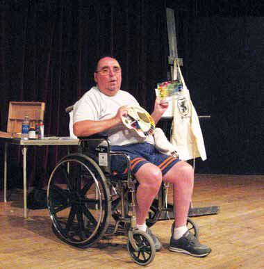 a man using a wheelchair and explaining something on stage