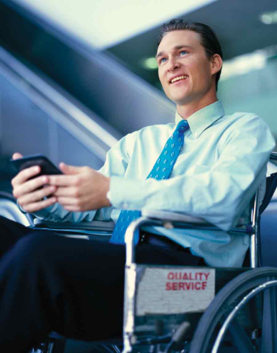 A photo of a man wearing a suit and using a wheelchair and a smart phone