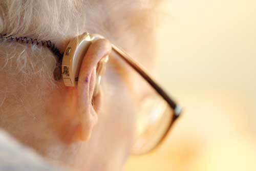 A photo of an older man using a hearing aid