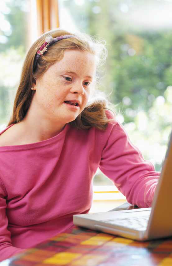 a photo of a girl with Down Syndrome looking at a laptop