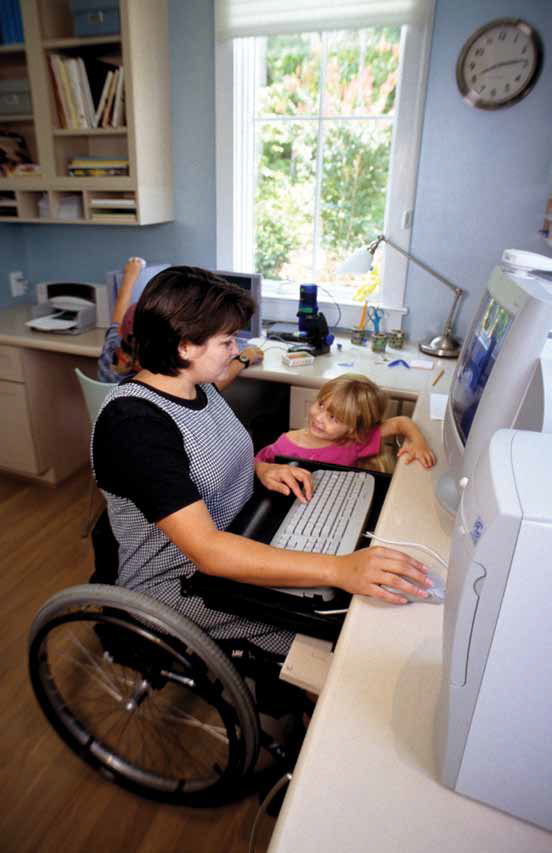 a photo of a mom and her little girl looking up information on the computer. the mom is using a wheelchair