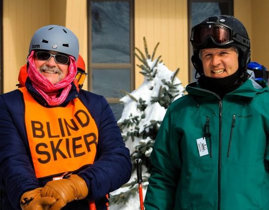a photo of an instructor working with a blind skier