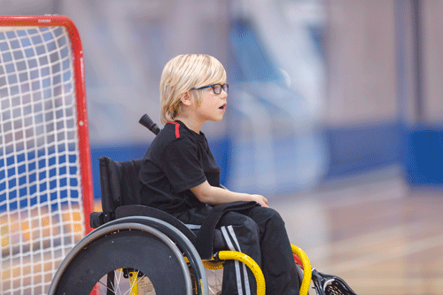 A photo of a boy using a wheelchair and playing goalie