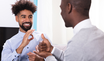 two men in suits having a conversation in ASL and smiling