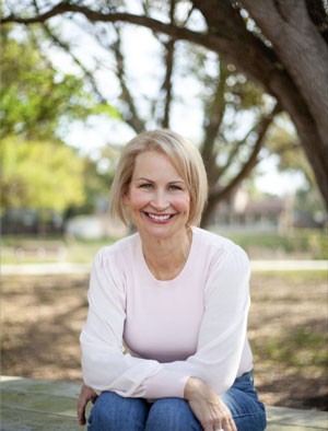 Dr. Russel sitting underneath a tree and smiling