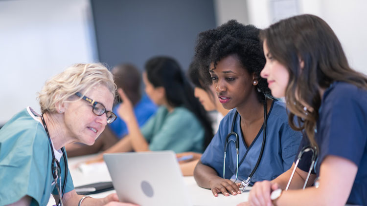 Healthcare professionals reviewing patient information together on a laptop in a clinical training setting